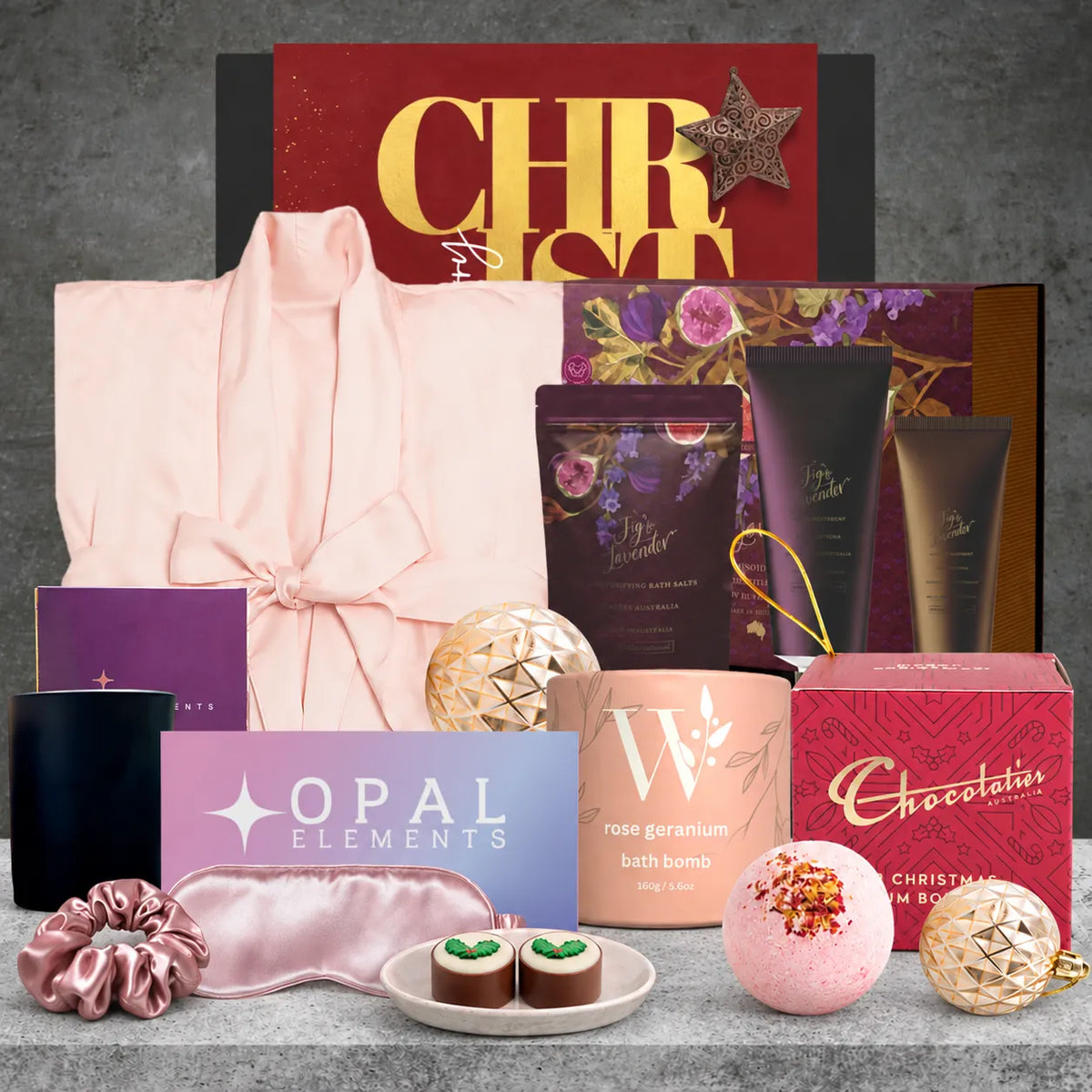 Rejuvenating Christmas self-care hamper featuring a satin bathrobe, fig and lavender body pamper set, bath bomb, silky eye mask, plum soy candle and Christmas chocolate